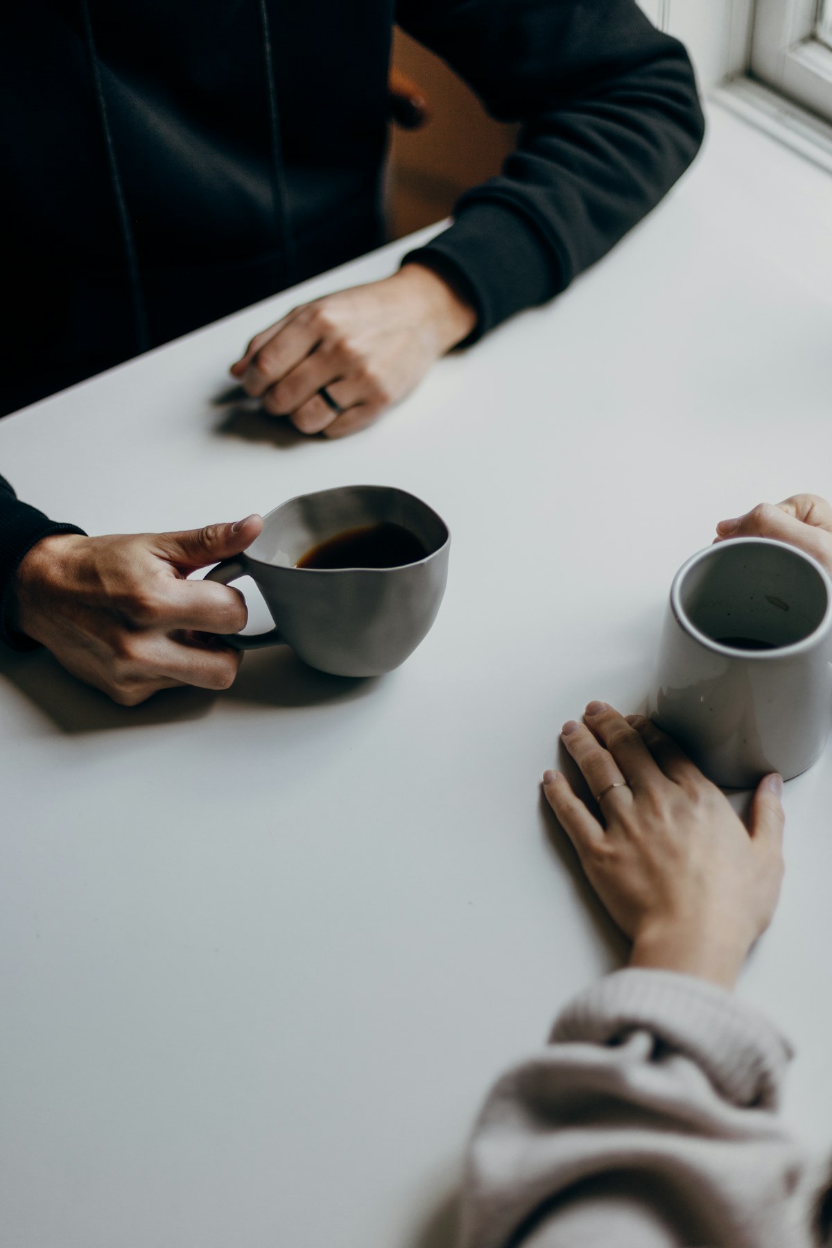 Two people holding mugs across a café table